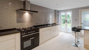 A modern kitchen with a gas stove, oven, and a stainless steel range hood. - 4 Bed Family Home In Windsor - By Tempstay (Old Windsor)