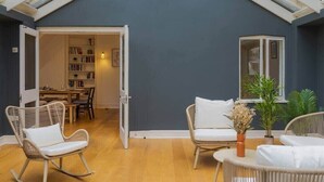A room with a sloped ceiling, wicker furniture, a bookshelf, and a dining area. - 4 Bed Family Home In Windsor - By Tempstay (Old Windsor)
