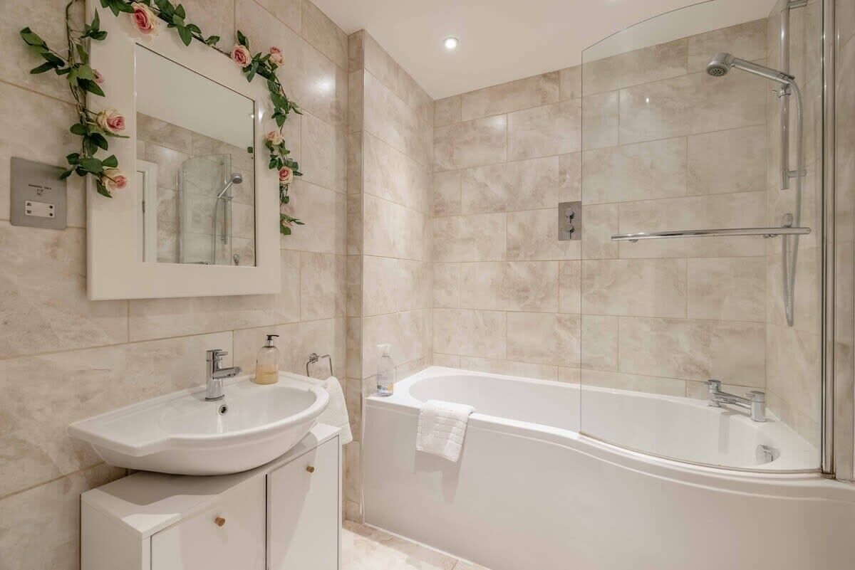 A bathroom with a sink, mirror, and bathtub.