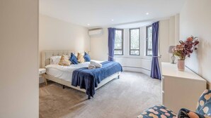 A bedroom with a bed, a desk, a chair, and a window with curtains. - Windsor Castle Views & Parking - By Tempstay (Berkshire)