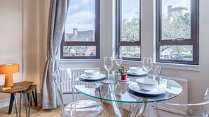 A dining area with a glass table, white plates, and clear chairs. - Windsor Castle Views & Parking - By Tempstay (Berkshire)