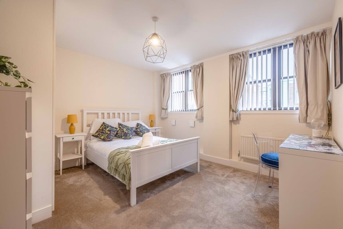 A bedroom with a bed, bedside tables, a desk, and a window with curtains.