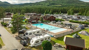 A campground with RVs, a swimming pool, and cabins surrounded by forested hills. - First Camp Bø  Telemark (Midt-Telemark)