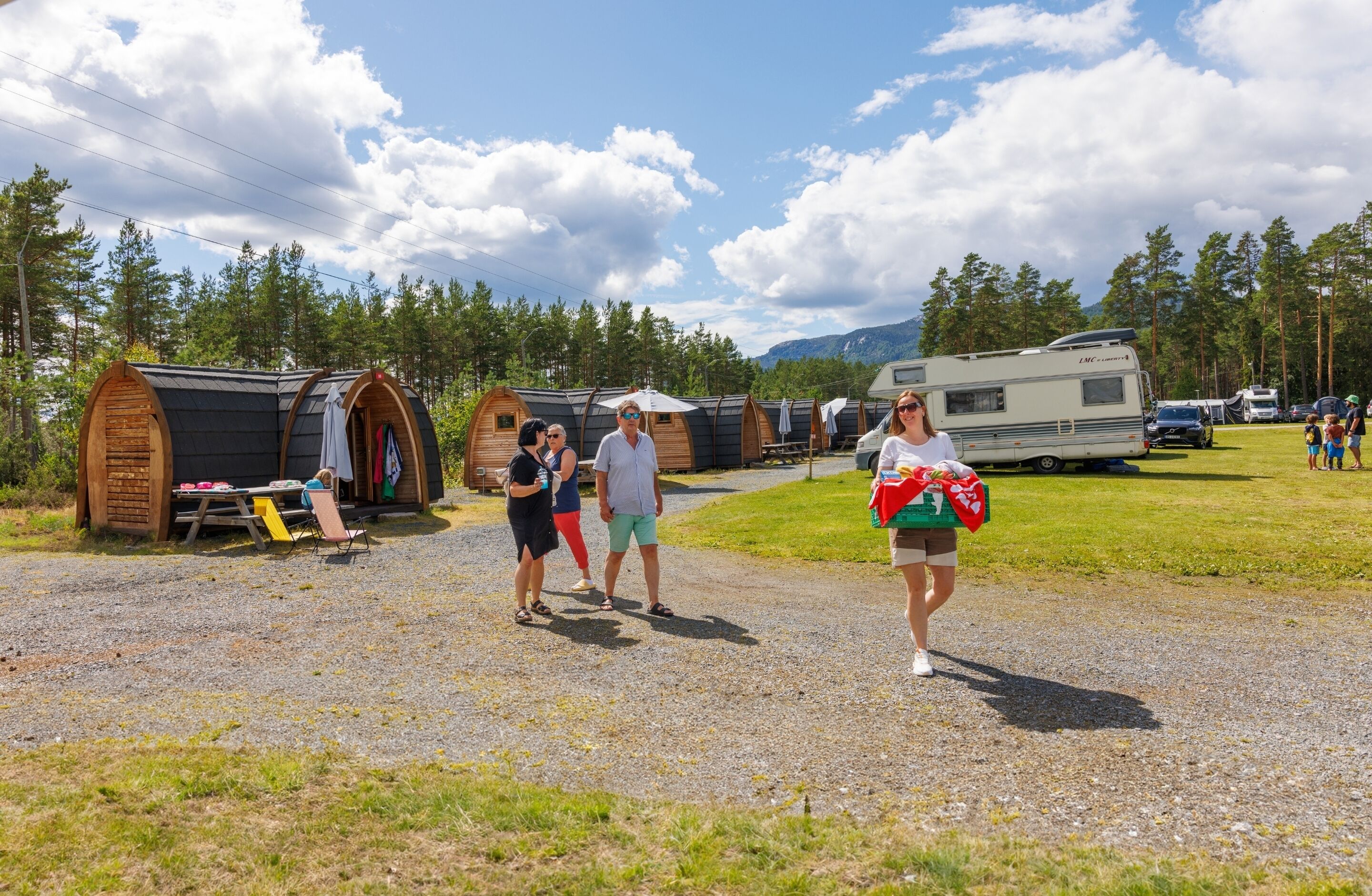 Ein Campingplatz mit Wohnmobilen, Holzhütten und einem Schotterweg.