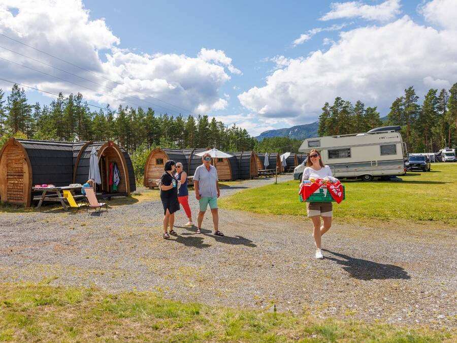 Ein Campingplatz mit Wohnmobilen, Holzhütten und einem Schotterweg.