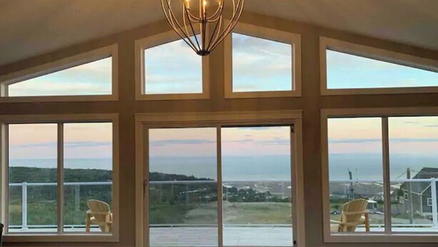 A spacious room with large windows offering a view of a landscape and a body of water.