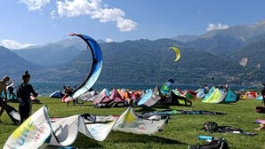 Un campo cubierto de césped con numerosas cometas y tiendas de campaña, lo que sugiere un evento para volar cometas.