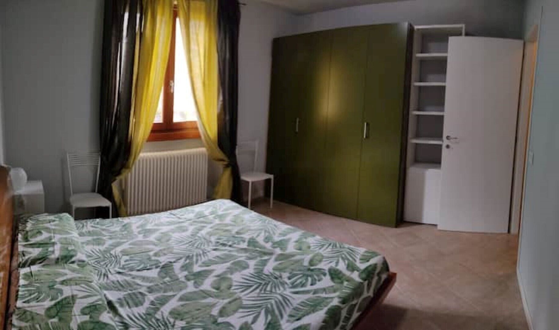 A bedroom with a bed, a wardrobe, and a chair.