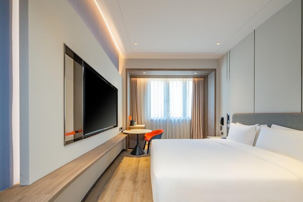A hotel room with a large bed, a flat-screen TV mounted on the wall, a small round table, and a chair. - Holiday Inn Express Suzhou Luzhi (Suzhou)