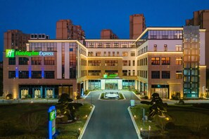 A Holiday Inn Express building with a modern design, large windows, and a well-lit entrance. - Holiday Inn Express Suzhou Luzhi (Suzhou)
