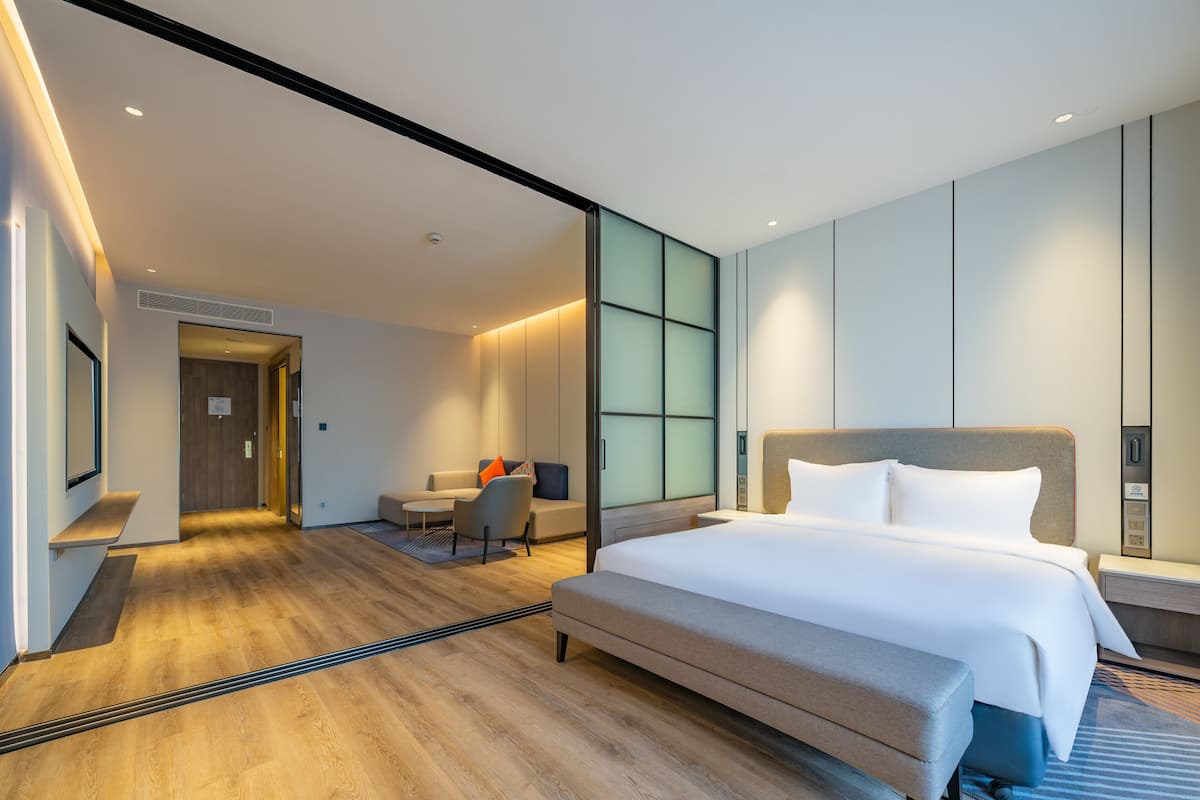 Quarto de hotel moderno com uma cama grande, uma mesa e um espaço de estar.