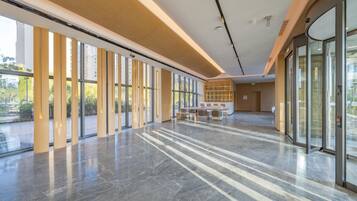 A spacious lobby with large windows, a marble floor, and a seating area.