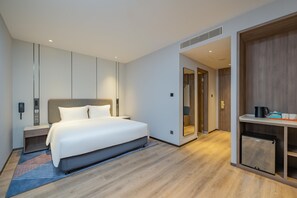 A modern hotel room with a bed, bedside table, nightstand, and a small refrigerator. - Holiday Inn Express Suzhou Luzhi (Suzhou)