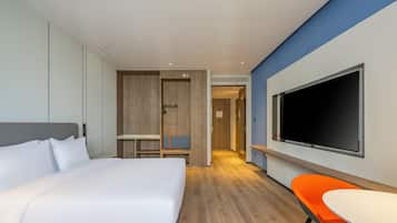 Una habitación de hotel moderna con una cama grande, un televisor, un escritorio y una silla.