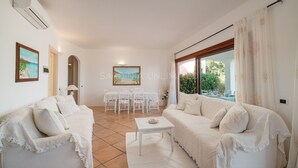 Un salon spacieux comprenant un ensemble de canapés, une table à manger avec des chaises et une grande fenêtre avec des rideaux.