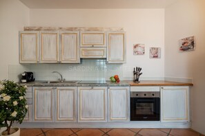 A kitchen with white cabinets, a built-in oven, and a coffee machine. - Villetta Ligea- SARDINIA UNLIMITED (Porto Cervo)