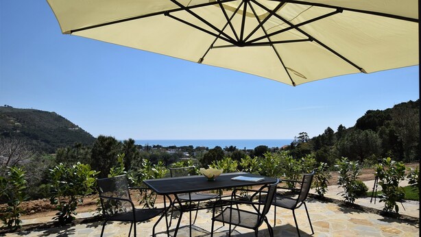 A patio with a table and chairs under a large umbrella, overlooking a scenic landscape. - App.to Jasmine, sea view 450 meters, with equipped garden. (Castellabate, fraz. Ogliastro Marina)