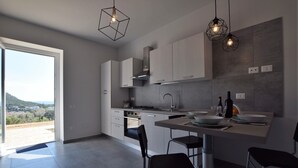 A modern kitchen with a large island, white cabinets, and a view of the outdoors. - App.to Jasmine, sea view 450 meters, with equipped garden. (Castellabate, fraz. Ogliastro Marina)
