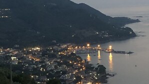 A coastal town at dusk with illuminated buildings along the waterfront, surrounded by hills. - App.to Jasmine, sea view 450 meters, with equipped garden. (Castellabate, fraz. Ogliastro Marina)
