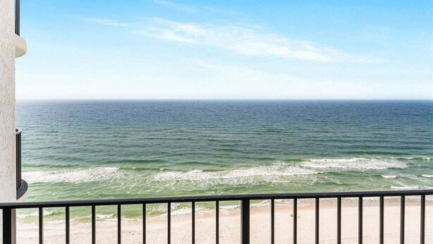 A balcony with a view of the ocean and beach.