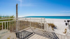 A beach view with a wooden deck and white railings.
