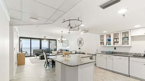 A modern kitchen with white cabinetry, granite countertops, and a central island.
