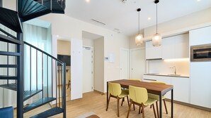 A modern kitchen with white cabinets, a wooden dining table, and yellow chairs. - Tandem Populo (Cádiz)