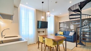 A modern apartment with a kitchen, dining area, living room, and a spiral staircase. - Tandem Populo (Cádiz)