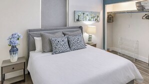 Une chambre à coucher moderne avec un lit, des tables de chevet, une lampe, un vase de fleurs et un tableau au mur.