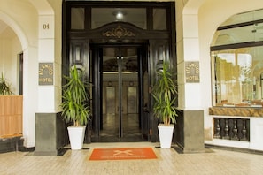 The entrance to the Atlantic Hotel with a double door, potted plants, and a doormat.