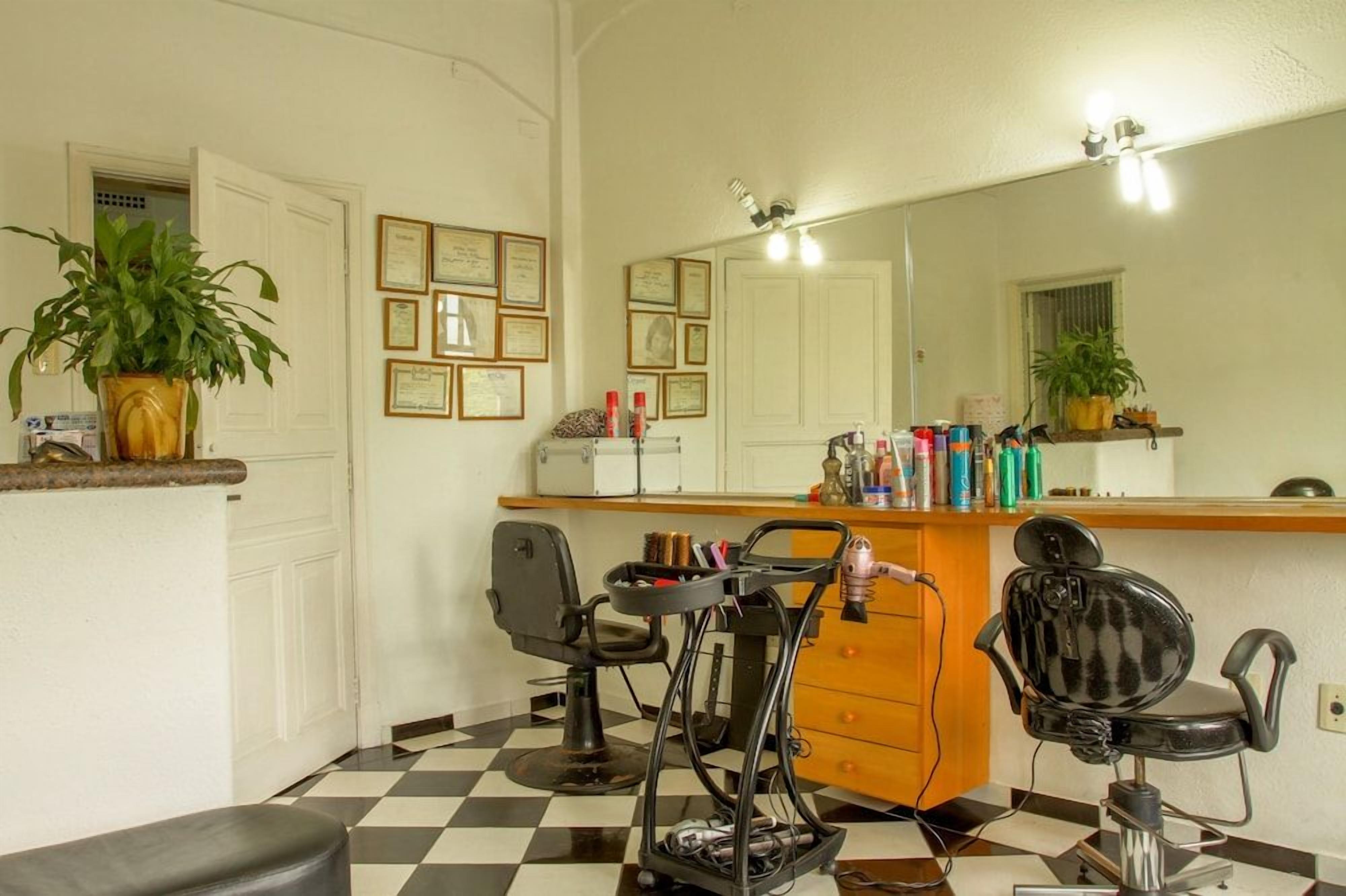 Ein Friseursalon mit zwei Stühlen, einem Spiegel und diversen Haarpflegeprodukten auf der Theke.