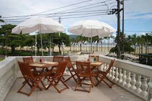 Un espace extérieur aménagé avec des tables et des chaises, des parasols blancs et une vue sur la plage.
