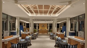 A hotel lobby with a central reception desk, seating area with chairs, and a skylight ceiling. - Avani+ Fares Maldives Resort (Fares)