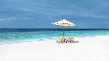Una playa de arena blanca, mar azul transparente y una sombrilla.