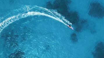 An aerial view of a boat creating a wake in a large body of water.