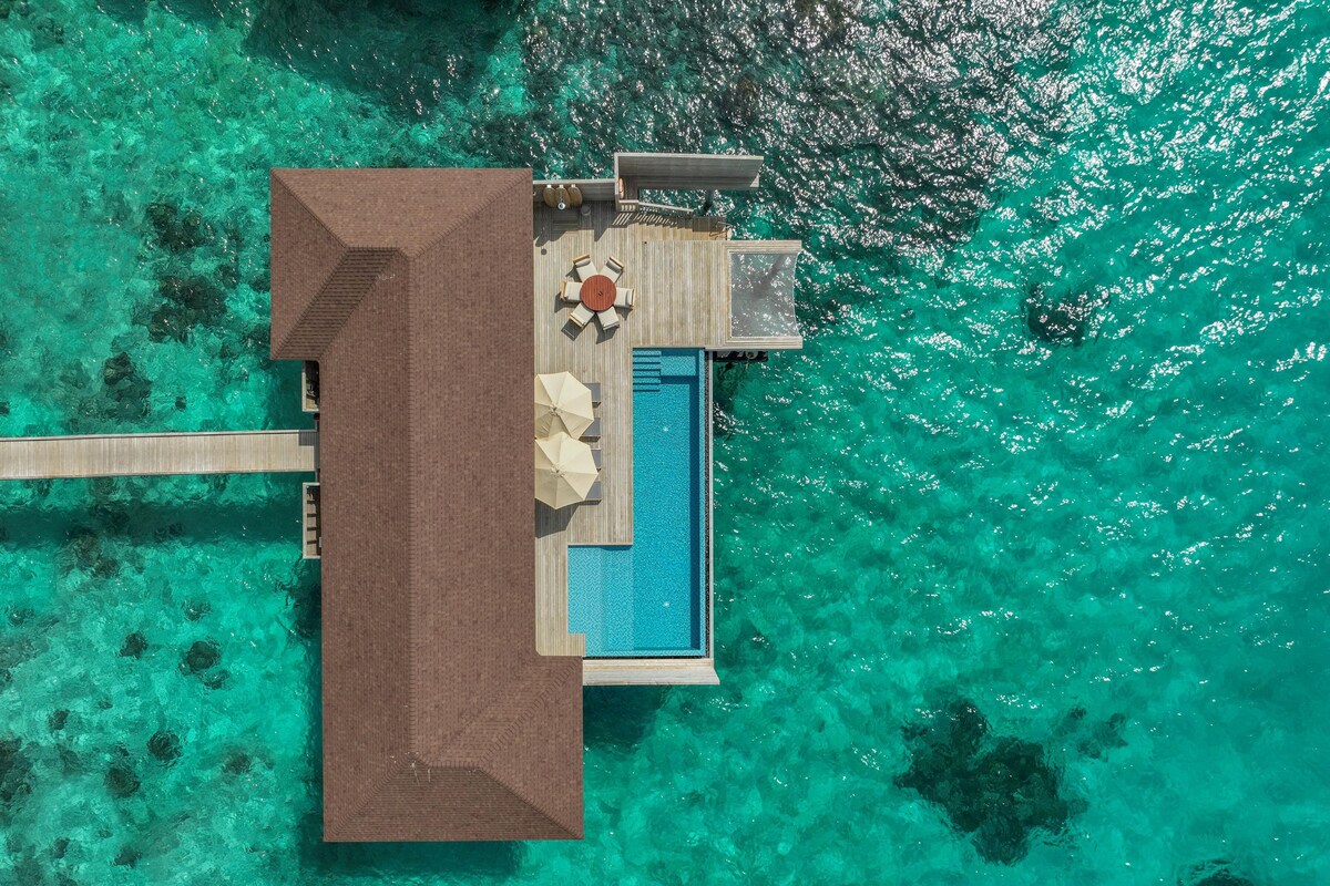 Vue aérienne d’un complexe hôtelier doté d’une terrasse en bois, d’une piscine et d’un espace repas.