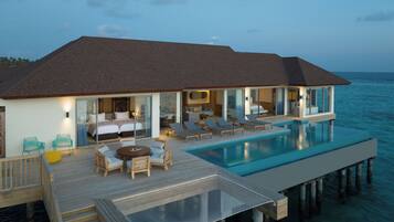 A modern overwater villa with a private infinity pool, multiple bedrooms, and a deck with outdoor seating.