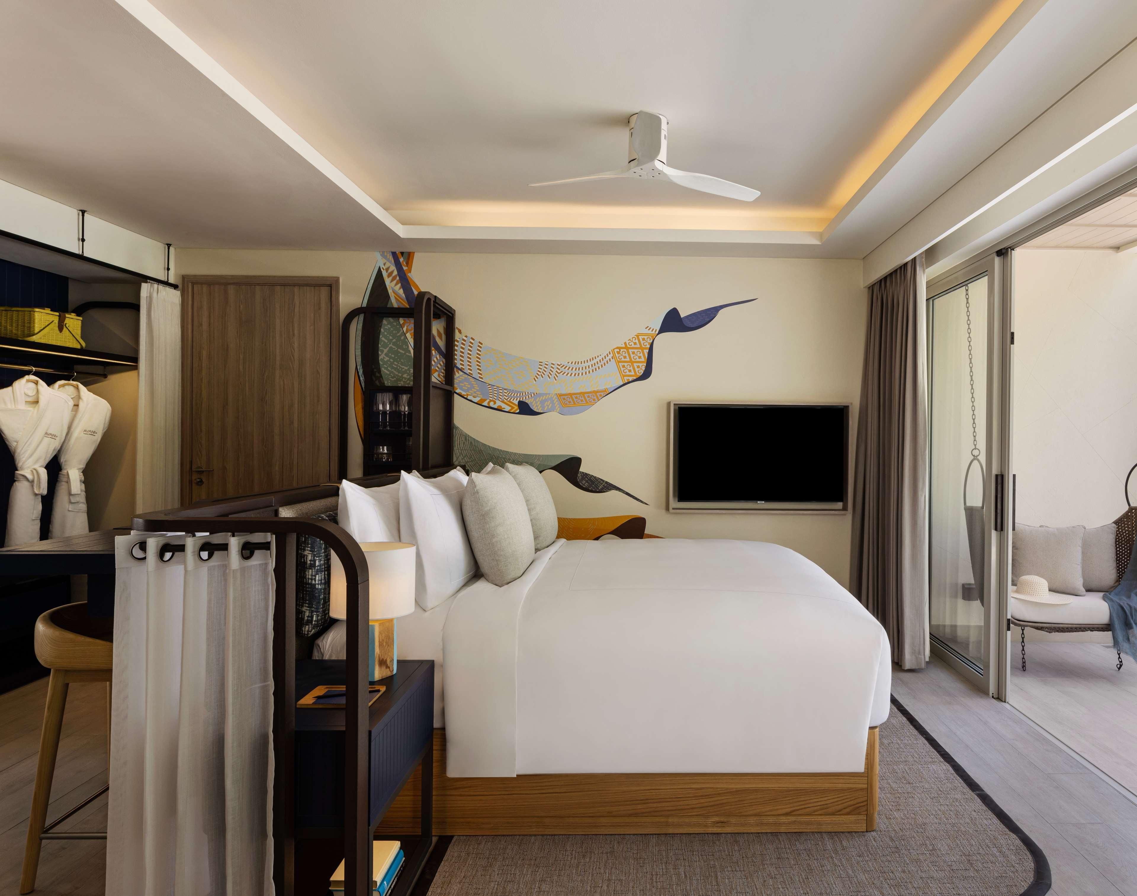 A hotel room with a bed, a desk, a chair, a TV, and a ceiling fan.