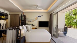 Une chambre d’hôtel moderne avec un grand lit, un ventilateur de plafond, une télévision et une vue sur la plage.