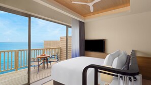 Een hotelkamer met een groot raam, een bed, een televisie en een balkon met een tafel en stoelen.