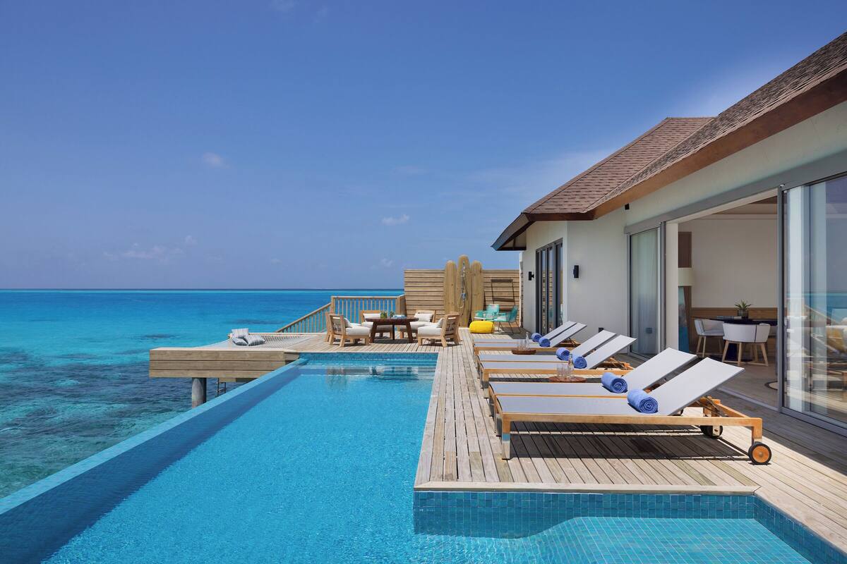 An infinity pool with lounge chairs and a wooden deck overlooking the ocean.