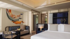 Une chambre d’hôtel moderne, dotée d’un grand lit, d’un canapé, d’une table à manger et d’une fresque murale décorative.