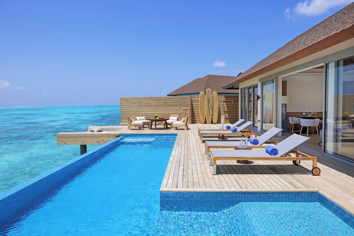 An infinity pool with lounge chairs and a wooden deck overlooking the ocean.
