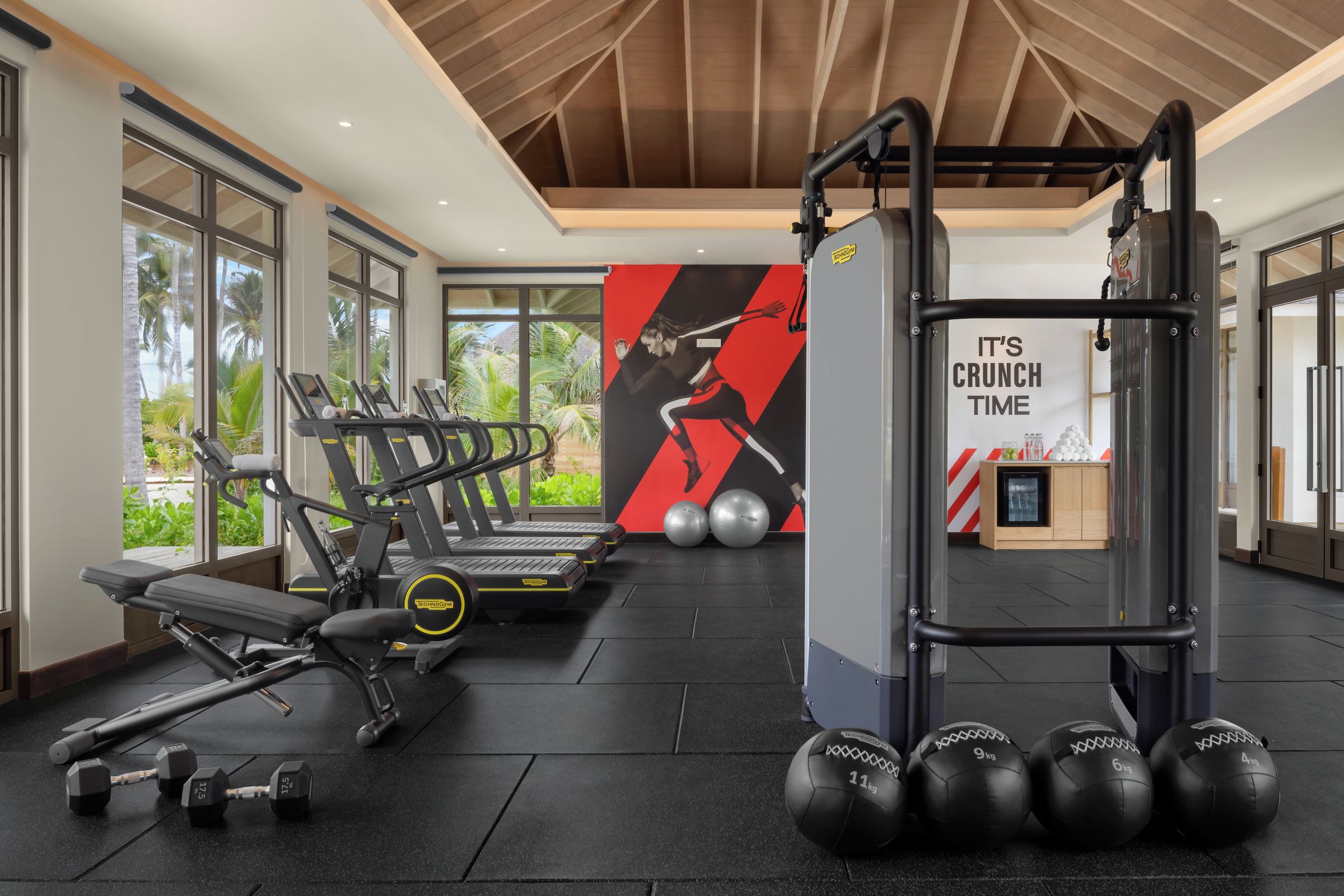 A modern gym with treadmills, dumbbells, and a squat rack.