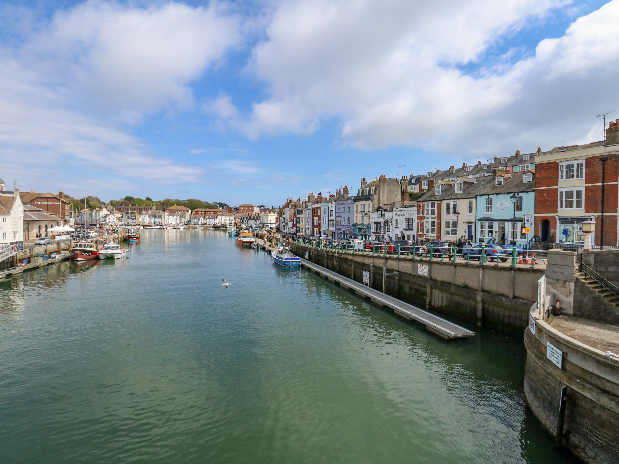 A harbor with boats docked, a pier, and buildings along the waterfront.
