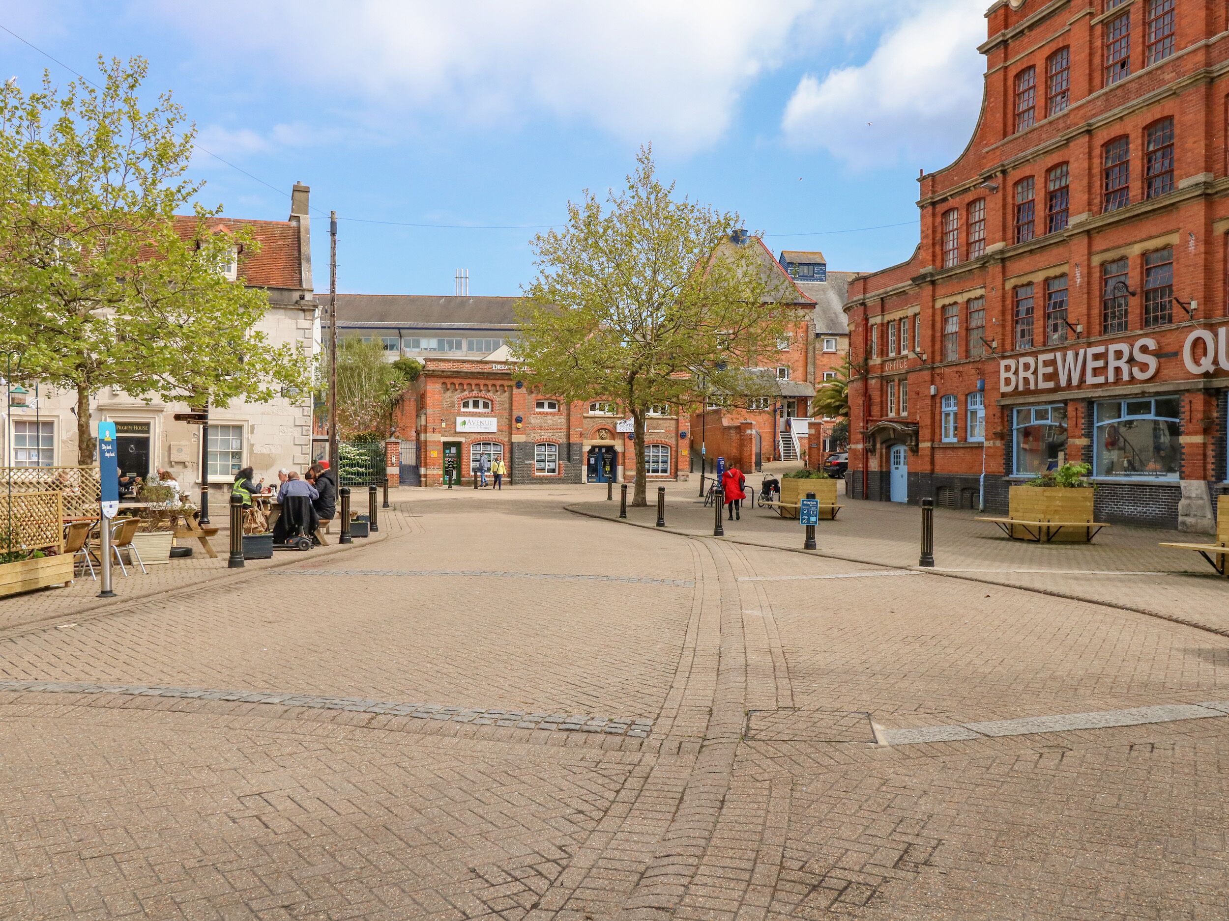 A public square with cobblestone pavement, historic buildings, and outdoor seating areas.