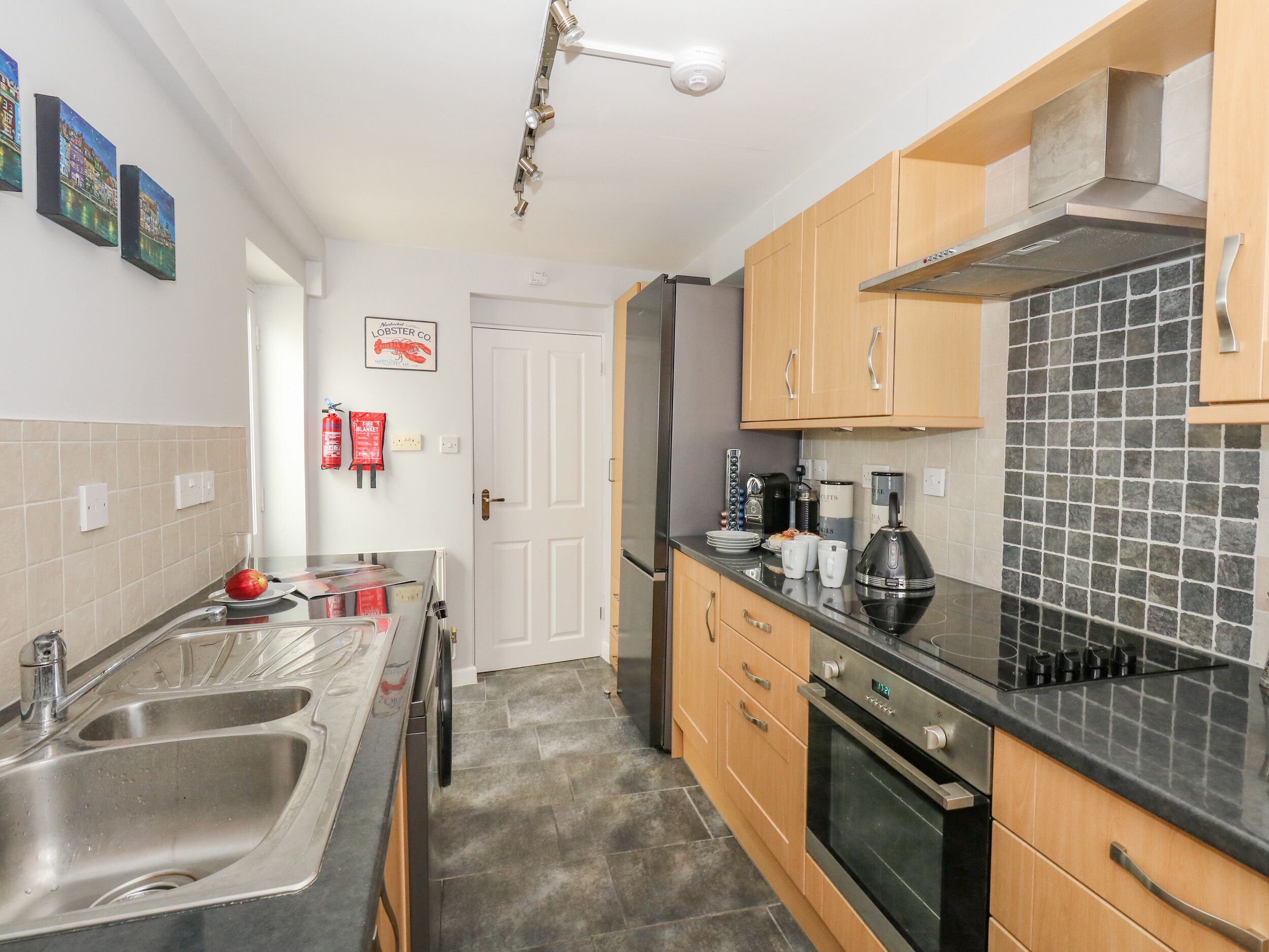 A modern kitchen with stainless steel appliances, wooden cabinets, and a tiled backsplash.