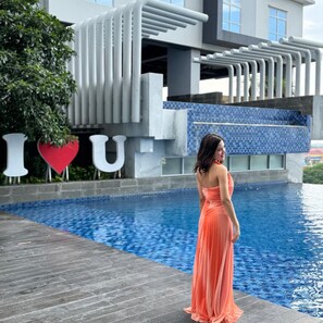 A person standing by a pool with a modern building in the background. - BeSS Mansion Hotel Surabaya (Wonocolo)
