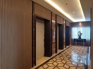 A hallway with a patterned floor, doors, and a wall-mounted sculpture. - BeSS Mansion Hotel Surabaya (Wonocolo)