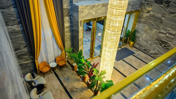 A modern lobby with marble flooring, a central column, seating area with chairs, and potted plants. - Exclusive Serene Hotel Abuja (Abuja)